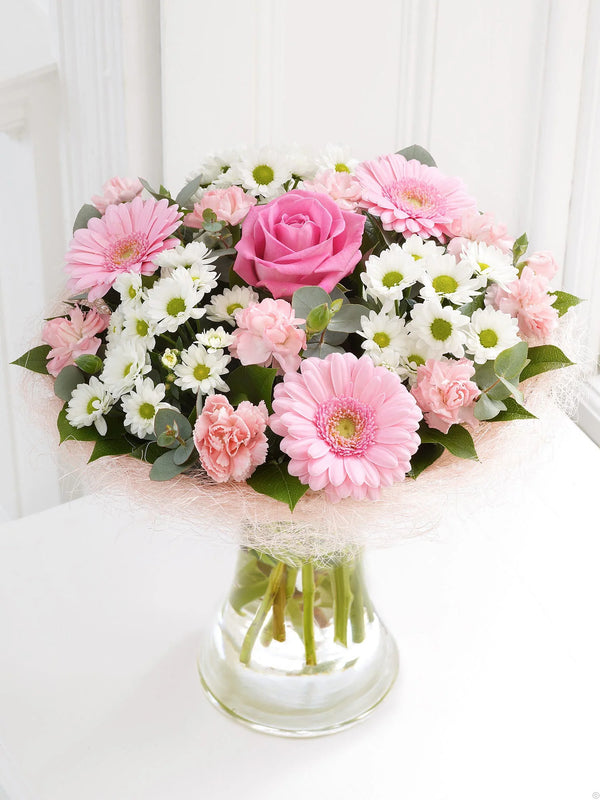 Bouquet with pink gerbera, pink roses, pink carnations, white chrysanthemums, and eucalyptus in a vase wrapped with pink net by florist dubai